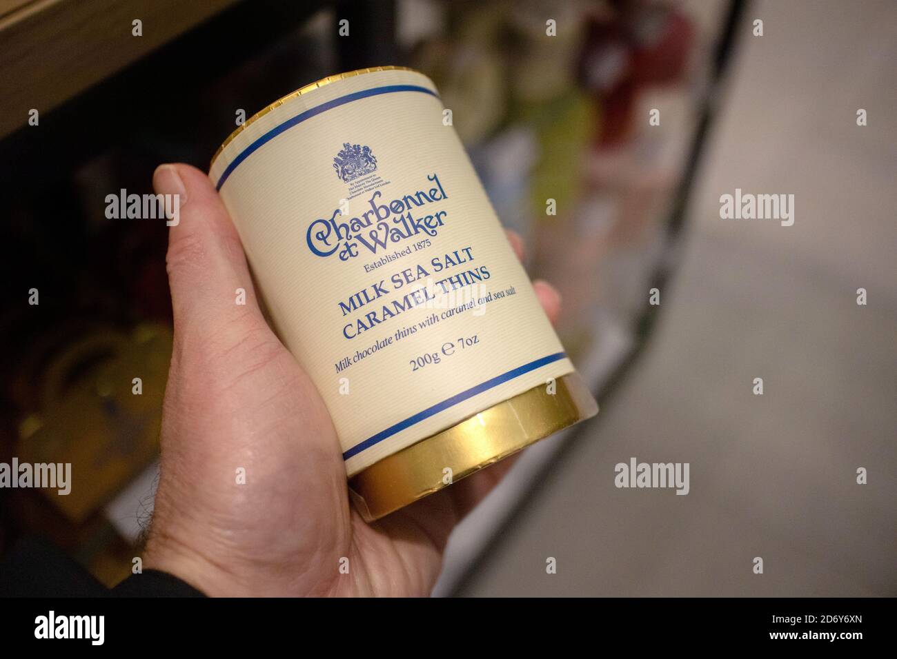 Hand hält eine Dose Charbonnel et Walker' Milk Sea Salt Karamelldosen. Charbonnel et Walker ist ein Unternehmen der Schokoladenhersteller mit Sitz in Bond St, London Stockfoto