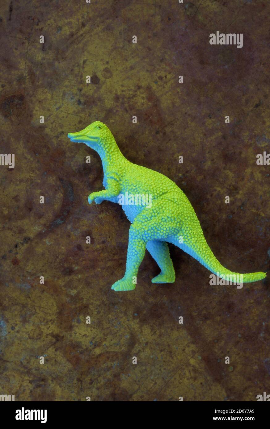 Modell des Dinosauriers Tyrannosaurus mit blauem Körper und hellgrün Zurück zu Fuß mit Hintergrund von Messing getrübt Stockfoto