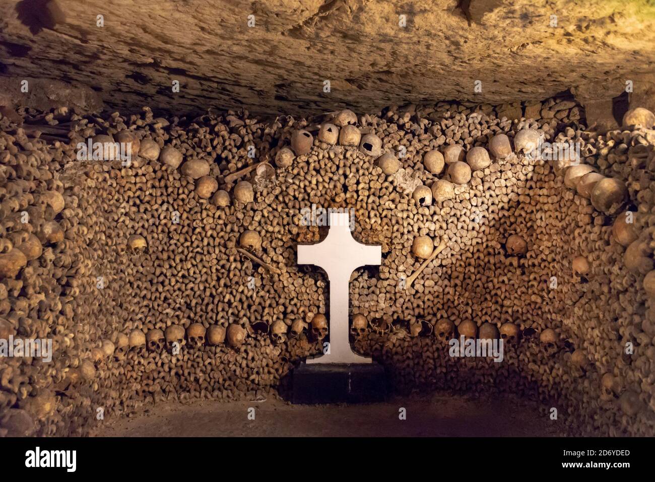 Stapel von Schädeln und Knochen mit einem weißen Kreuz in den Katakomben von Paris, Frankreich Stockfoto