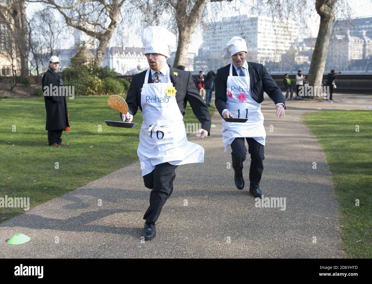 Der Abgeordnete Julian Huppert (links) und der Journalist Tom Bradby nehmen am Parliamentary Pancake Race 2011 Teil, um das Bewusstsein für Rehab in Victoria Tower Gardens im Zentrum von London zu schärfen. Stockfoto