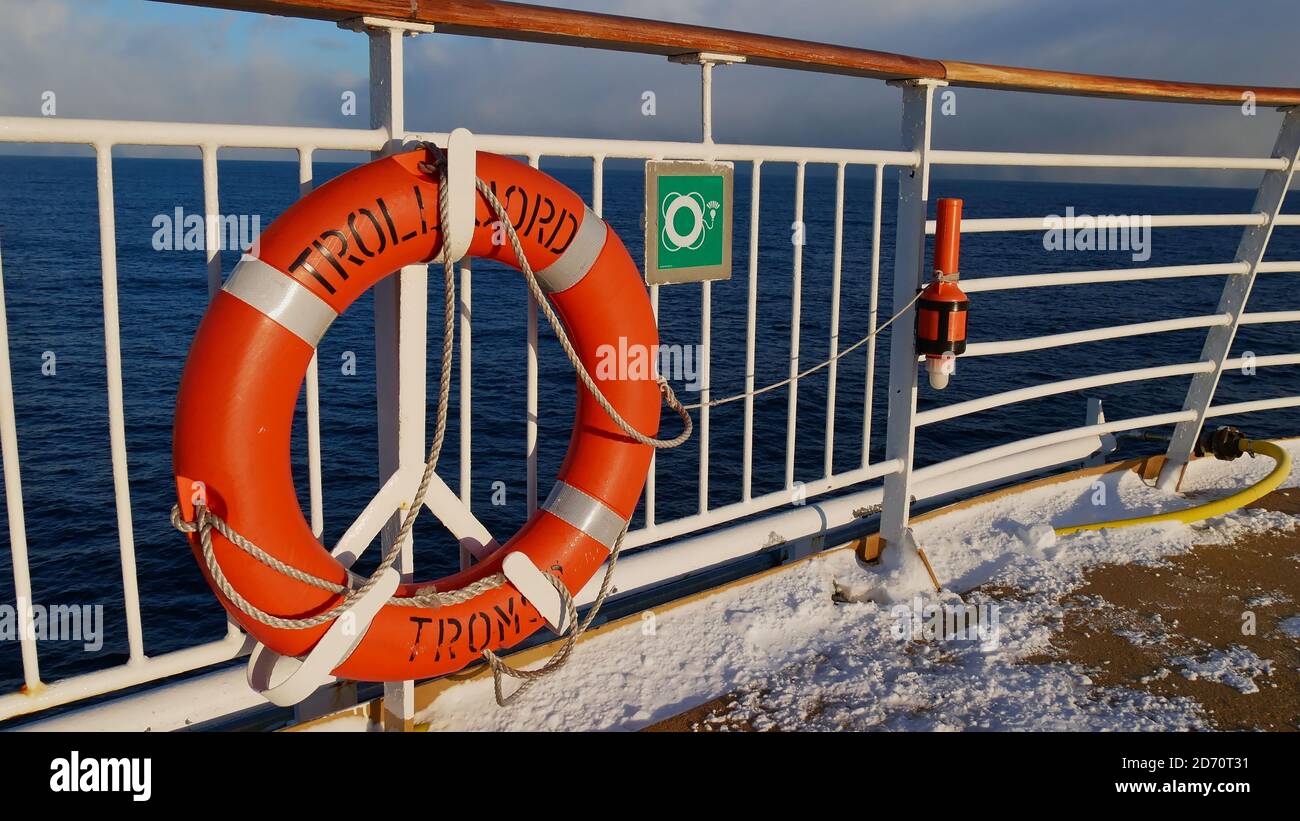 Sørøysundet, Norwegen - 03/02/2019: Orangefarbener Rettungsgürtel mit dem Schiffsnamen, der an der Reling des Oberdecks des Hurtigruten Kreuzfahrtschiffes montiert ist. Stockfoto