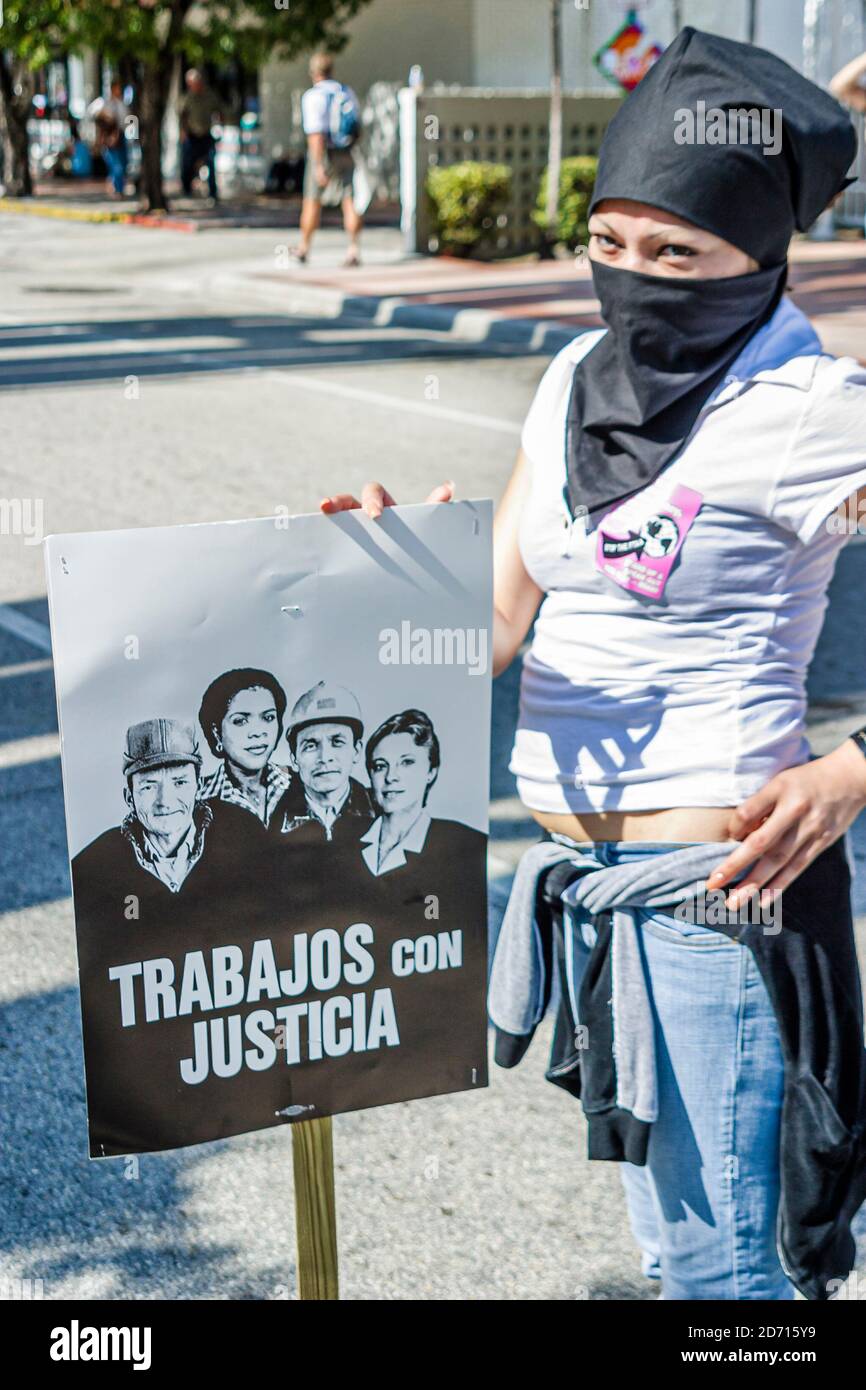 Miami Florida, Biscayne Boulevard, Freihandelszone der Amerikaner Gipfel FTAA-Demonstrationen, Demonstrator Protesterin Frau weibliche Gesicht bedeckt, Schild Poster Stockfoto