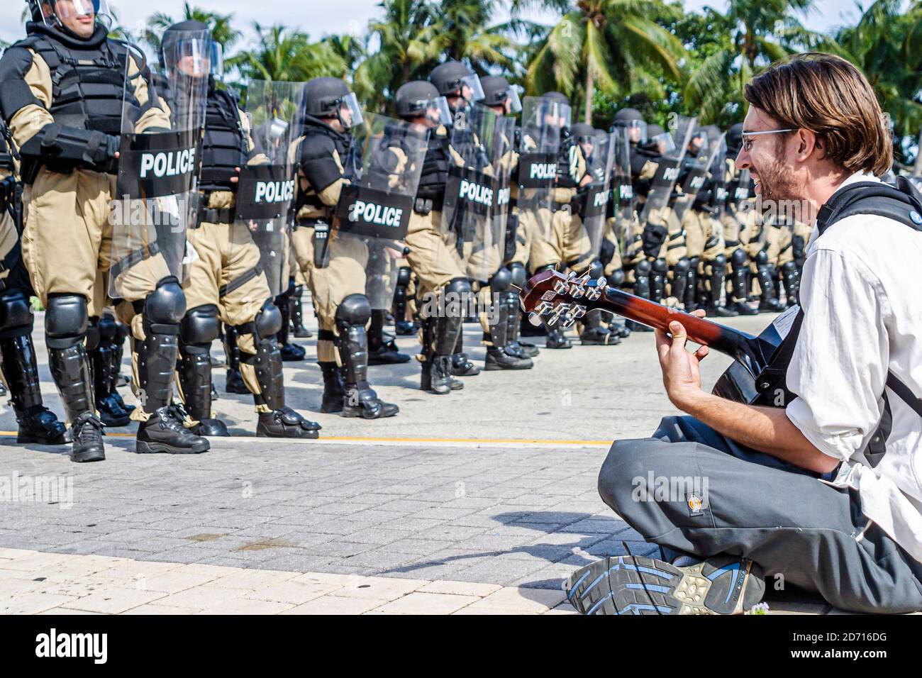 Miami Florida, Biscayne Boulevard, Freihandelszone des Amerikanergipfels FTAA-Demonstrationen, protestantischer Studierender, der an der Polizeilinie sitzt, rührende Zahnradschilder Stockfoto