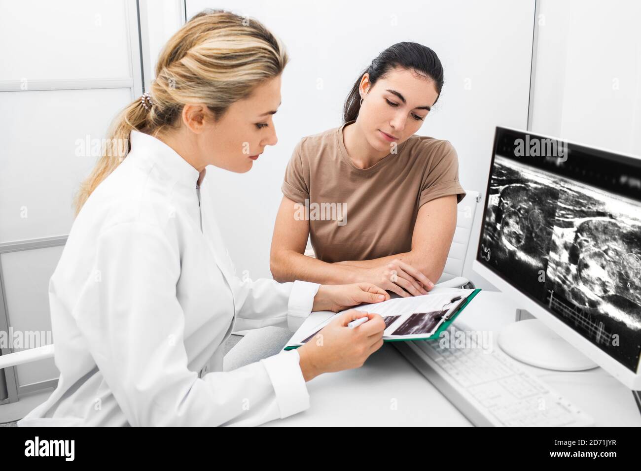 Endokrinologe Beratung der Frau, Arzt analysiert den Ultraschall der Schilddrüse des Patienten. Behandlung von Thyreotoxikose und Hypothyreose Stockfoto