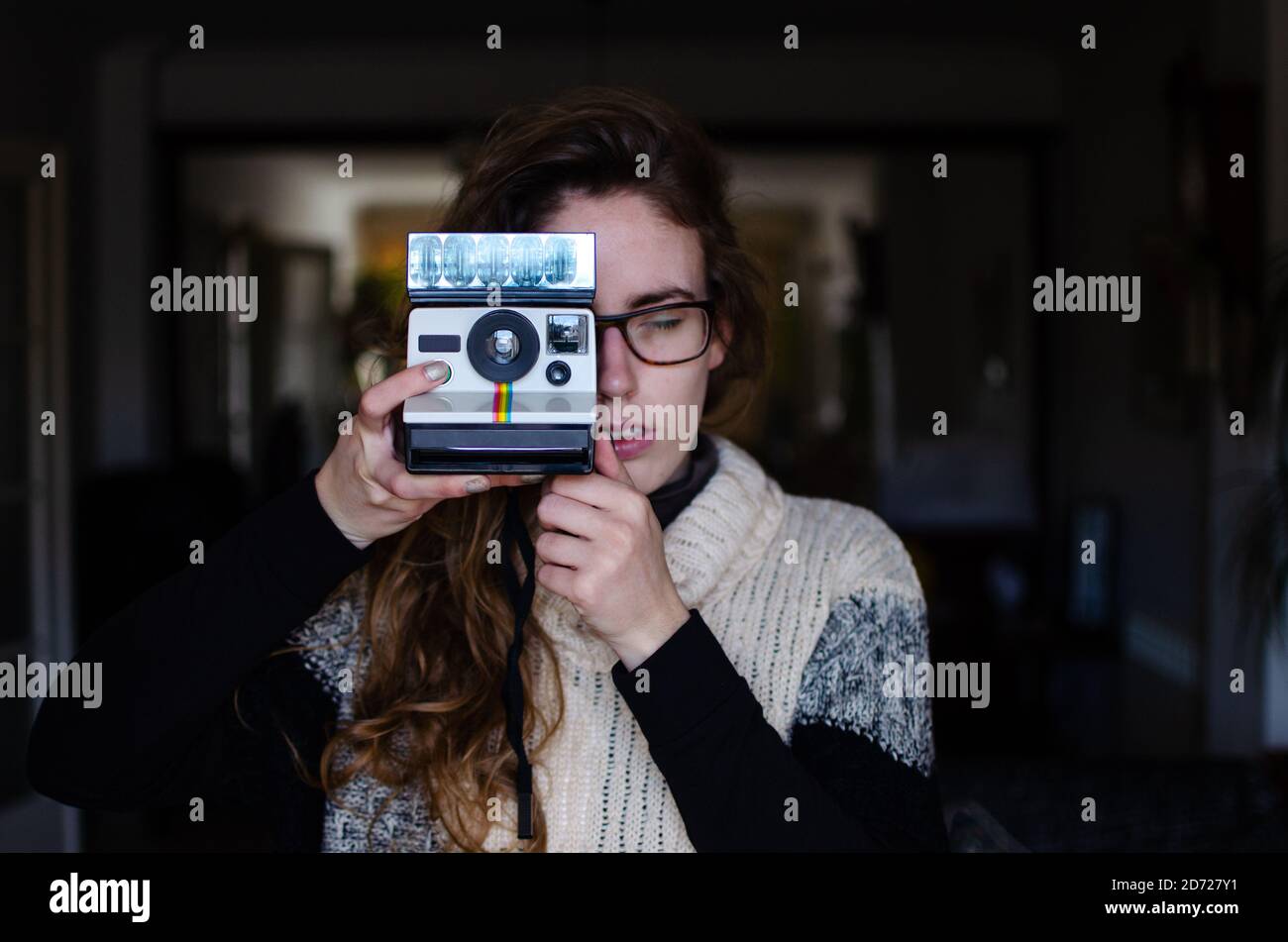 Kaukasische Mädchen mit dunkelblonden Haaren mit einer alten automatischen Druck polaroid Kamera. Stockfoto