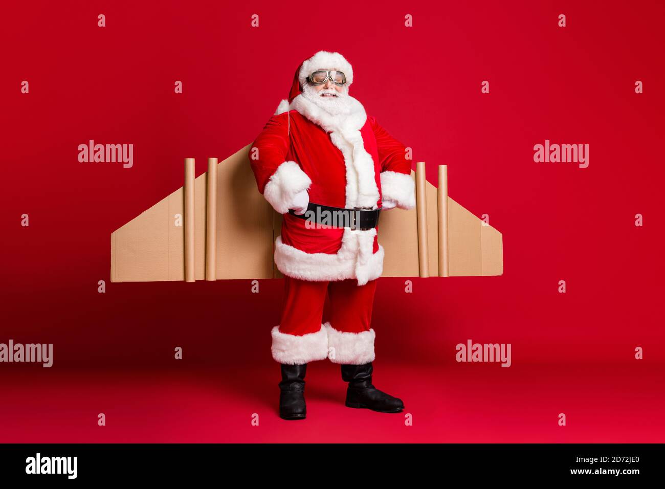 Foto in voller Länge von pensionierten Opa weißen Bart Jetpack Hände Hüften selbstsicher Vorbereitung rund um die Welt fliegen Reise tragen weihnachtsmann Kostüm Mantel Stockfoto