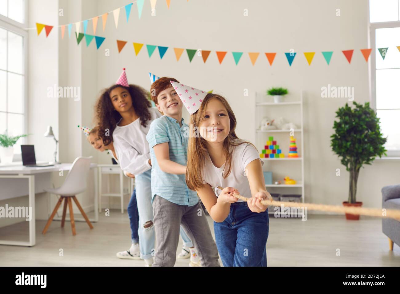 Gruppe glücklicher multirassischer Kinder, die auf der Geburtstagsfeier Tauziehen spielen Zu Hause Stockfoto