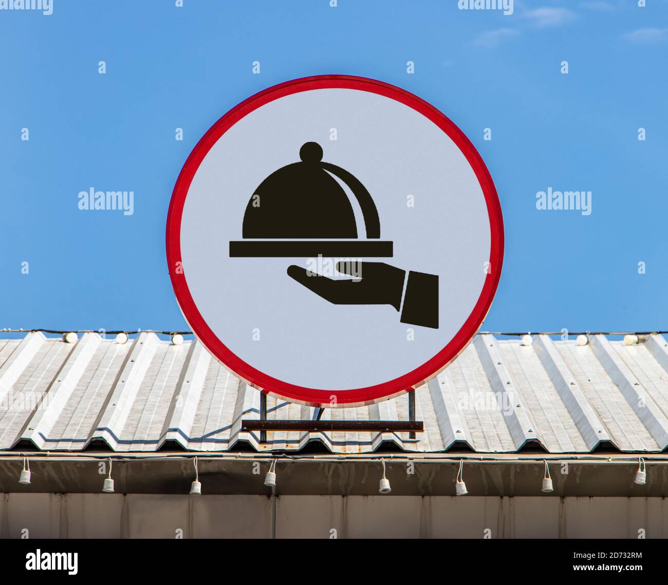 Auf einem Dach ist eine Circle Plakatwand mit Symbol-Handhalteabdeckung über dem Essen als Symbol für das Restaurant installiert. Stockfoto