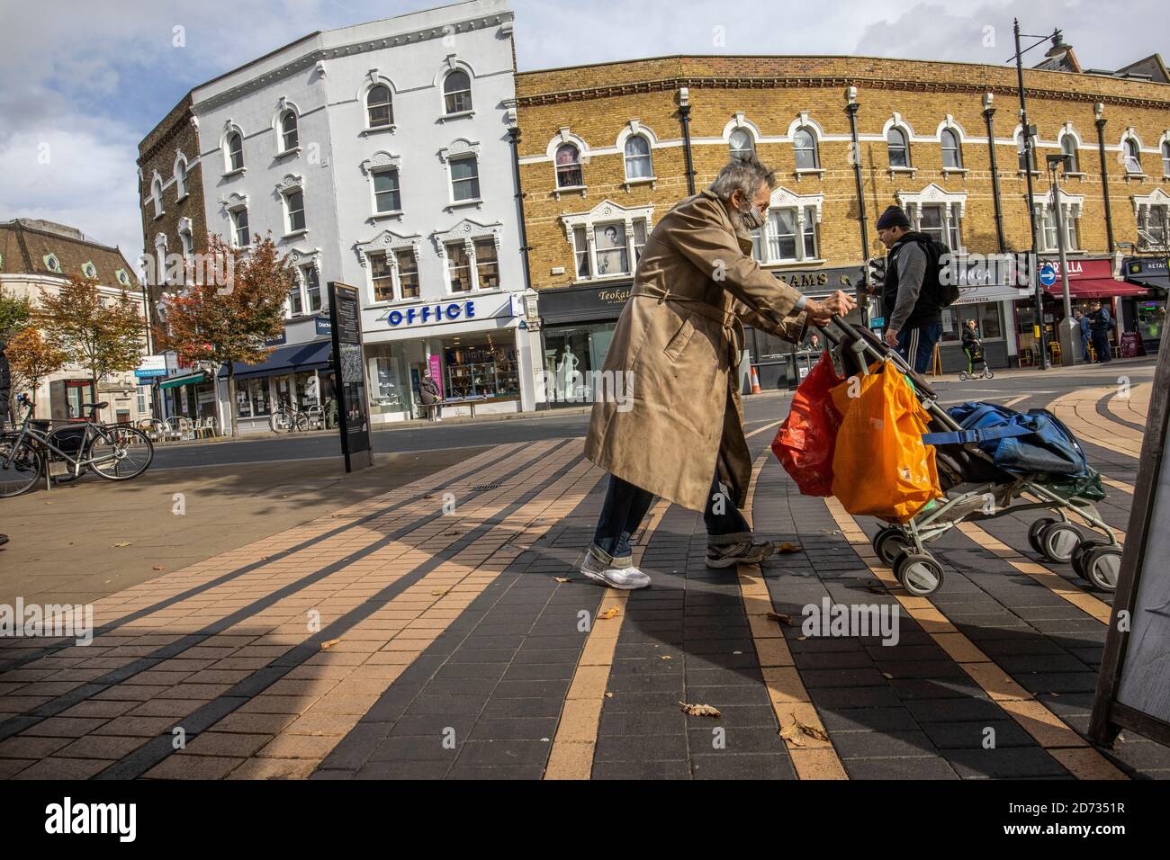 Obdachloser, der den Bürgersteig im Stadtzentrum von Wimbledon, Südwest-London, England, Großbritannien überquert Stockfoto
