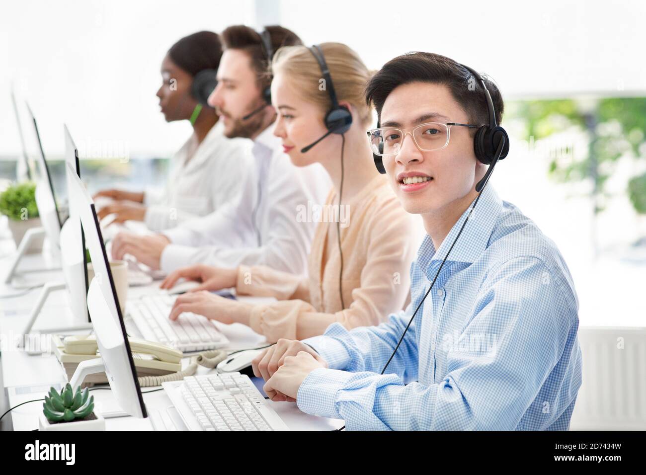 Asiatischer Callcenter-Manager, der lächelt und die Kamera im hellen Büro anschaut, Platz für Text Stockfoto