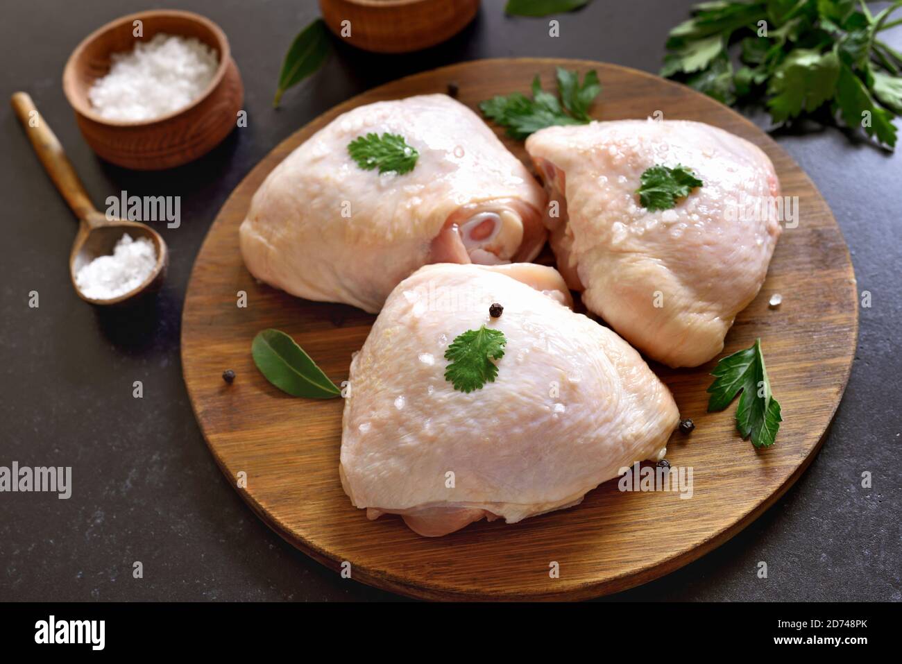 Rohes Hühnerschenkel auf Holzschneidebrett Stockfoto