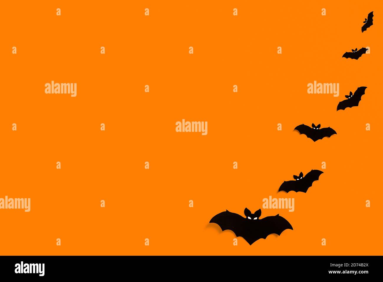 Silhouetten von schwarzen Papier Fledermäuse auf einem orangen Hintergrund bilden einen Rahmen, eine Herde von schwarzen Fledermäusen auf einem orangen Hintergrund, Halloween-Konzept, Copy Space Stockfoto