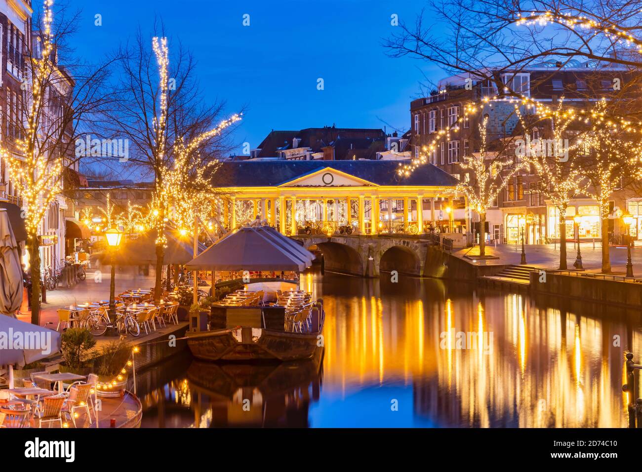 Alte Ansicht des niederländischen Oude Rijn-Kanals mit Brücke, historischen Gebäuden und weihnachtsbeleuchtung im Stadtzentrum von Leiden, Niederlande Stockfoto