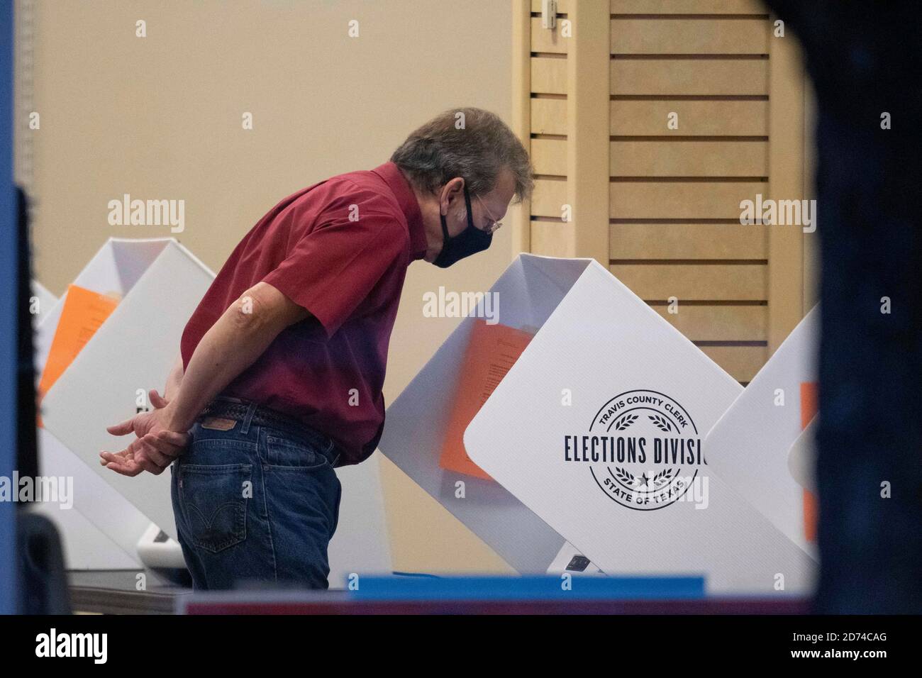 Austin, Texas 20. Oktober 2020: Maskierter Travis Count-Wähler Terry Welch schaut während der frühen Wahlperiode in Texas über einen Stimmzettel auf einem elektronischen Wahlcomputer. Die Grafschaft hat durchschnittlich eine Rekordzahl von 35,000 Wählern pro Tag mit zwei Wochen vor der Wahl am 3. November. Die Texaner haben bisher mehr als vier Millionen Stimmen in der Frühwahl abgestimmt. Kredit: Bob Daemmrich/Alamy Live Nachrichten Stockfoto