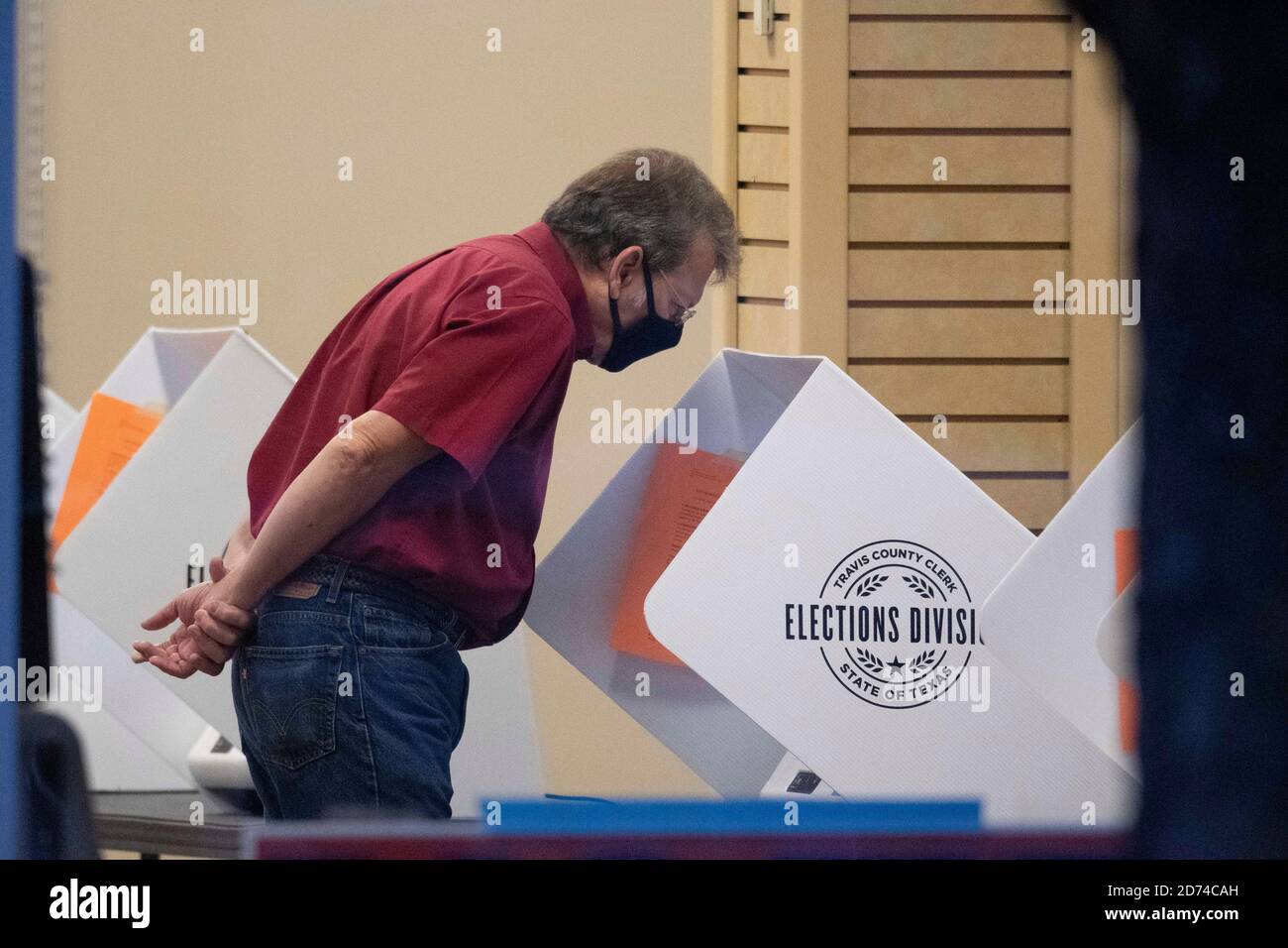 Austin, Texas 20. Oktober 2020: Maskierter Travis Count-Wähler Terry Welch schaut während der frühen Wahlperiode in Texas über einen Stimmzettel auf einem elektronischen Wahlcomputer. Die Grafschaft hat durchschnittlich eine Rekordzahl von 35,000 Wählern pro Tag mit zwei Wochen vor der Wahl am 3. November. Die Texaner haben bisher mehr als vier Millionen Stimmen in der Frühwahl abgestimmt. Kredit: Bob Daemmrich/Alamy Live Nachrichten Stockfoto