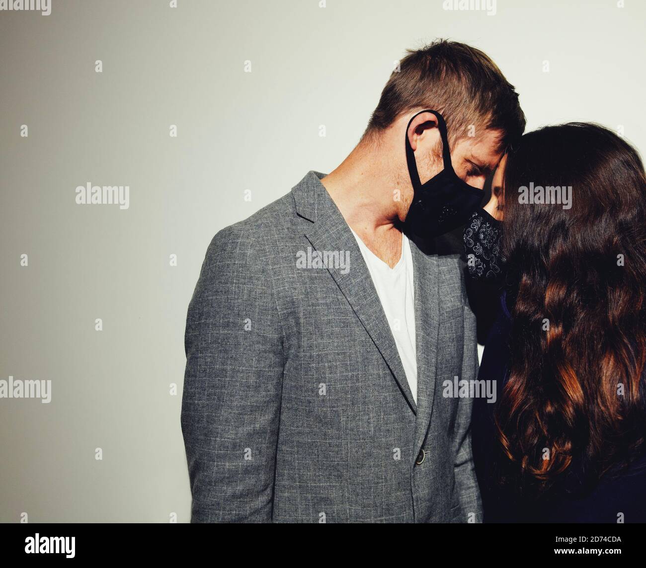 Schönes junges Paar in der Liebe, trägt modische Schutzmasken für Pandemie. Horizontale Komposition, Kopierbereich, weißer Hintergrund. Stockfoto