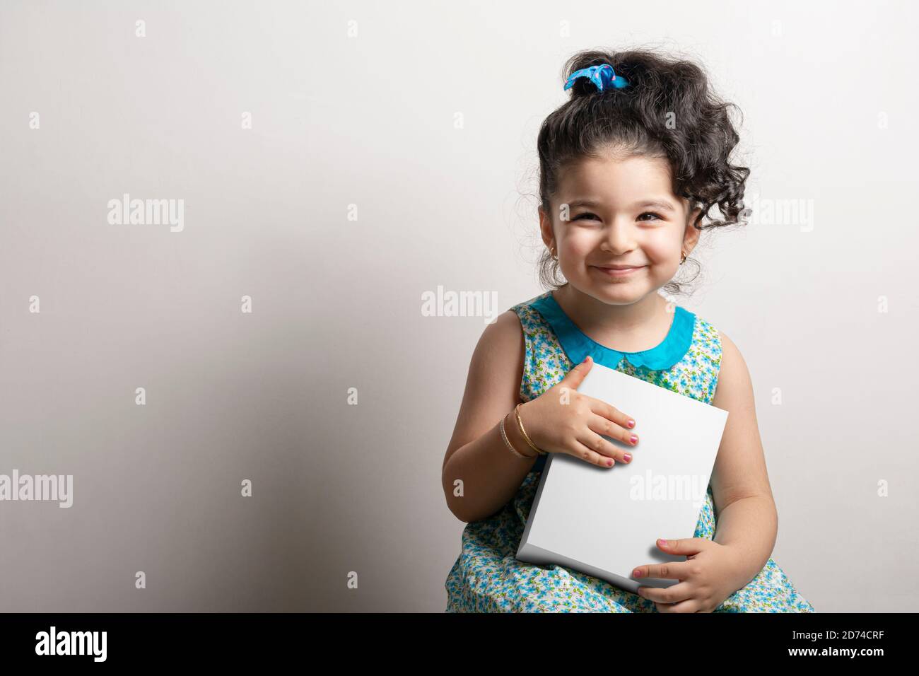 Kleines Mädchen hält eine kleine kubische Box in den Händen, editierbare Mock-up-Serie Vorlage bereit für Ihr Design, Auswahlpfad enthalten. Stockfoto