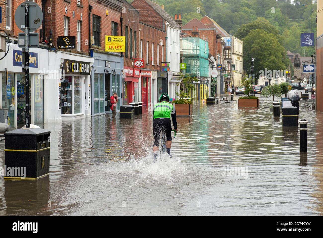 Winchester, England, UK 27/08/2020 EIN Radfahrer, der durch Hochwasser auf der High Street in Winchester nach schweren Regenfällen durch Sturm Francis. Stockfoto