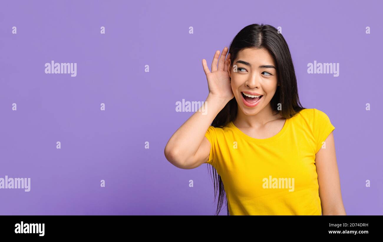 Klatsch-Konzept. Neugierige asiatische Frau, die Hand in der Nähe des Ohrs hält und versucht, Informationen zu hören Stockfoto
