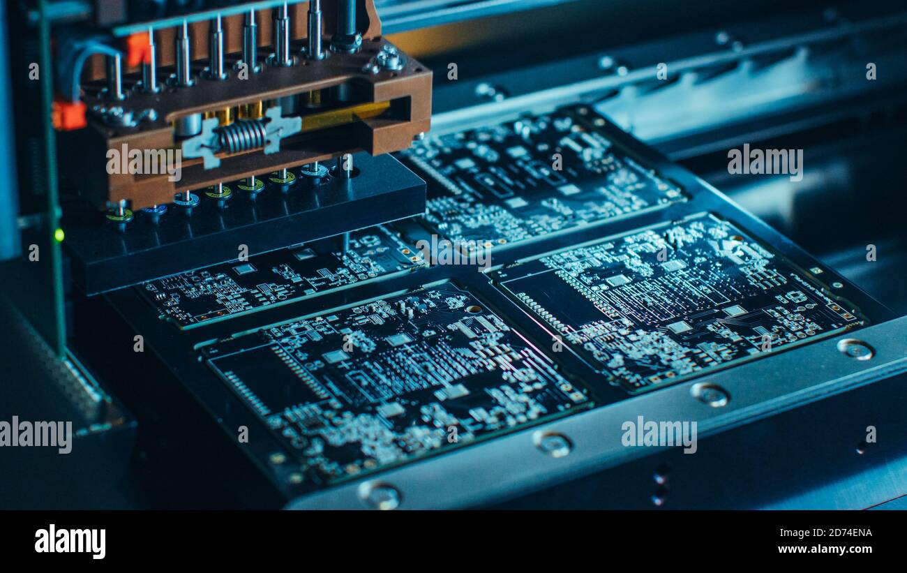 Nahaufnahme der elektronischen Leiterplatte, die mit einem automatisierten Roboterarm montiert wird, Surface Mounted Technology, die Mikrochips verbindet Stockfoto