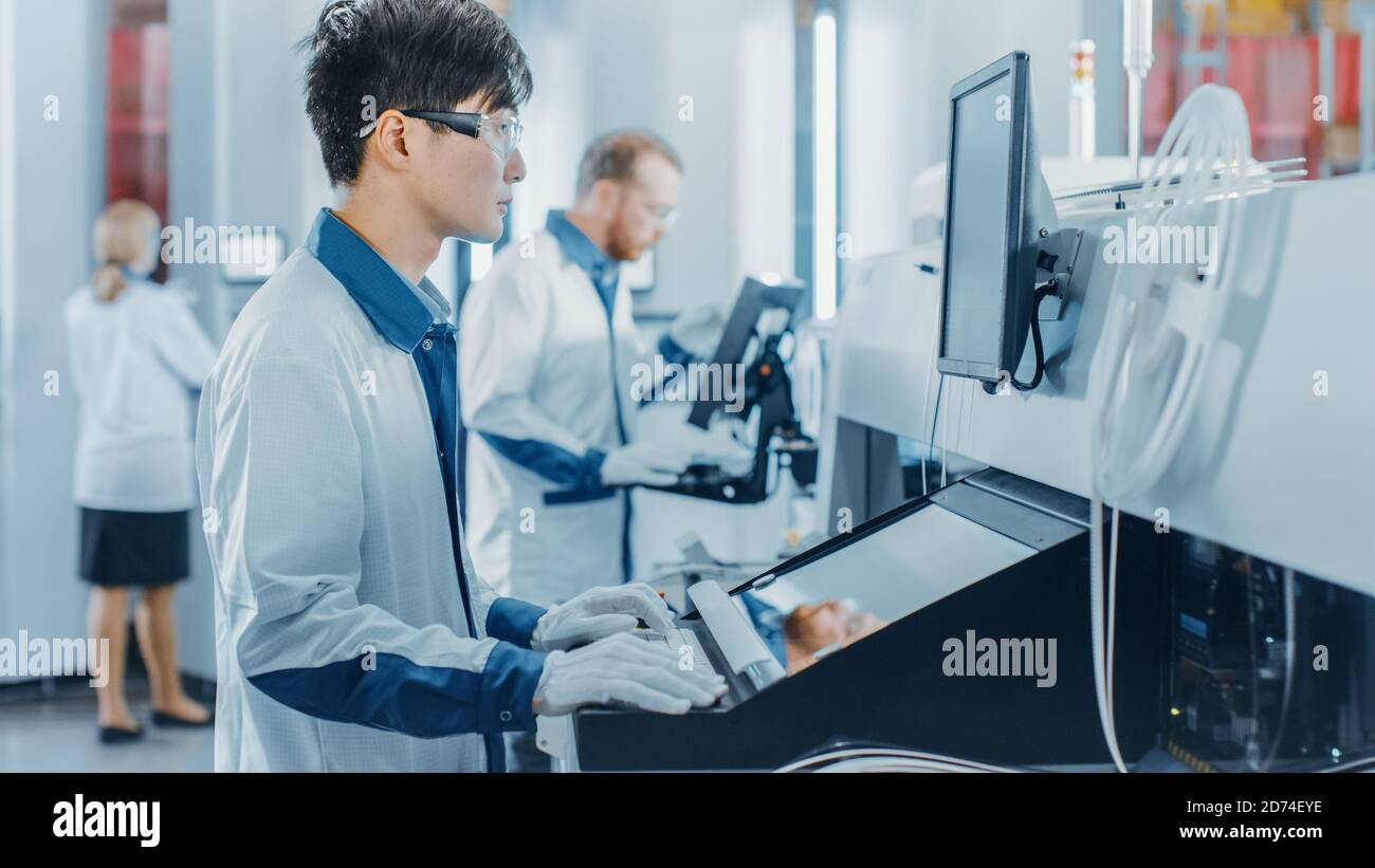 In der High-Tech-Fabrik verwendet Asian Engineer Computer für die Programmierung Pick and Place Elektronische Maschinen für die Leiterplattenmontage Linie Stockfoto