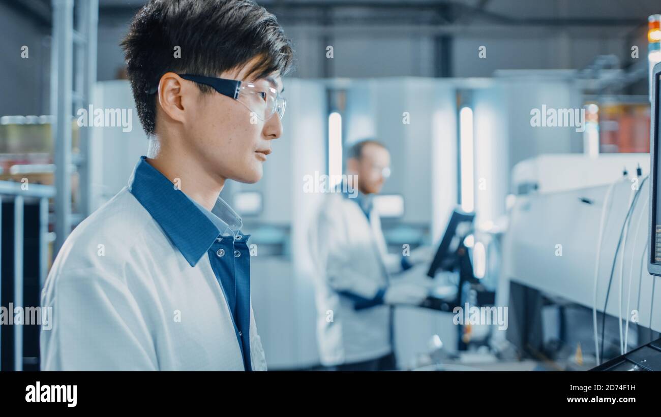 Porträt eines asiatischen Ingenieurs in der High Tech Factory Verwendet Computer für die Programmierung Pick and Place elektronische Maschinen für Leiterplatte Stockfoto