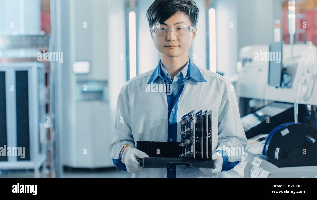 Auf High-Tech-Fabrik asiatischen Arbeiter hält Batch mit elektronisch gedruckt Leiterplatte montiert unter Verwendung von Surface Mount Technology on Wählen und platzieren Stockfoto