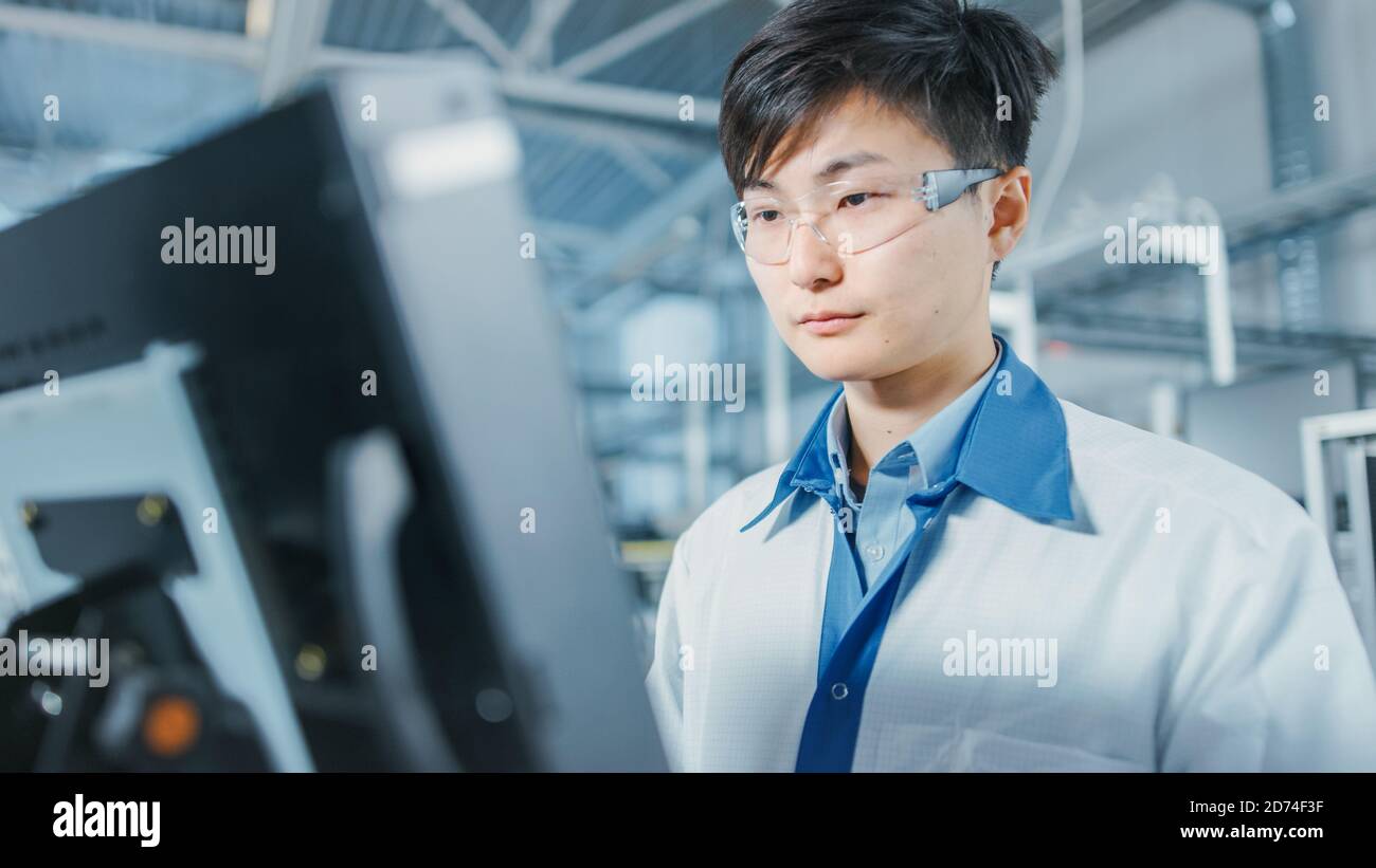 Portrait Aufnahme des asiatischen Ingenieurs in der High Tech Factory Computer für die Programmierung Pick and Place Elektronische Maschinen für gedruckt Leiterplatte Stockfoto