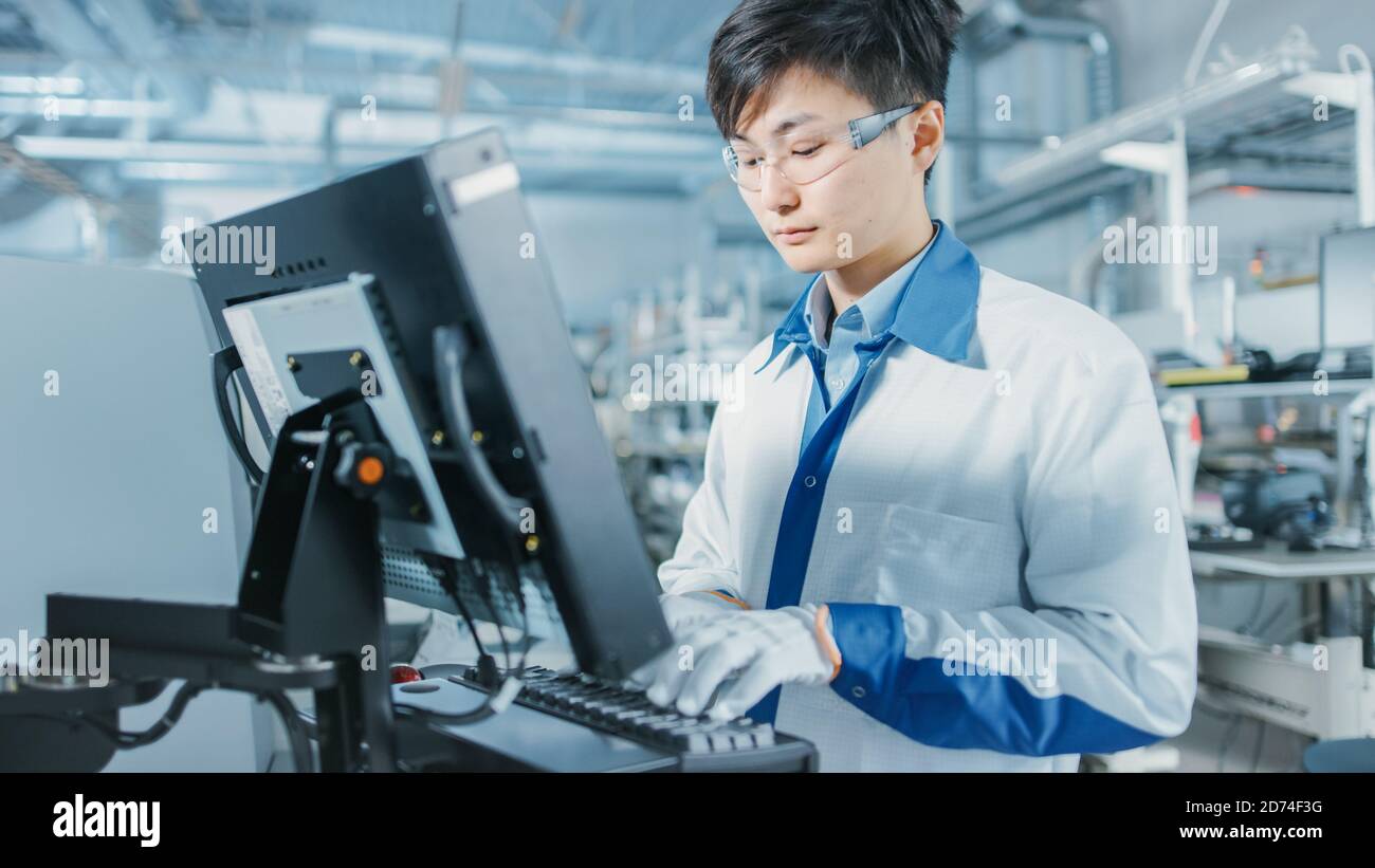 In der High-Tech-Fabrik verwendet Asian Engineer Computer für die Programmierung Pick and Place Elektronische Maschinen für Leiterplatten Oberfläche Montieren Sie Die Baugruppe Stockfoto