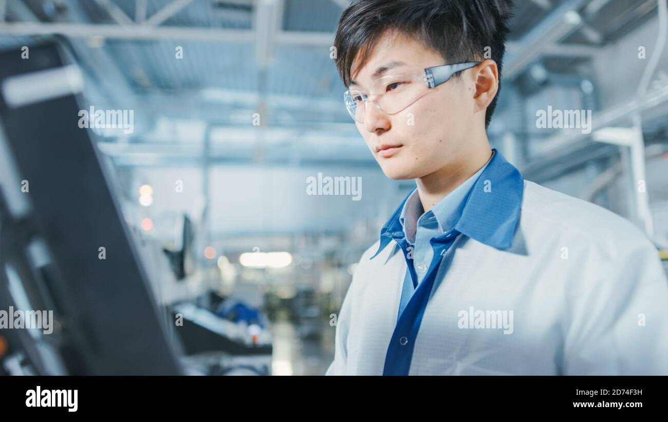 Portrait Aufnahme des asiatischen Ingenieurs in der High Tech Factory Computer für die Programmierung Pick and Place Elektronische Maschinen für gedruckt Leiterplatte Stockfoto