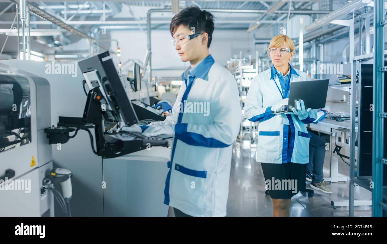 In der High-Tech-Fabrik verwendet Asian Engineer Computer für die Programmierung Pick and Place Elektronische Maschinen für Leiterplatten Oberfläche Montieren Sie Die Baugruppe Stockfoto