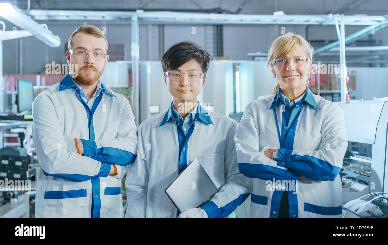 Auf High-Tech Factory: Portrait von drei professionellen Ingenieuren, die mit gekreuzten Armen posieren. Im Hintergrund der elektronischen Leiterplattenbaugruppe Stockfoto
