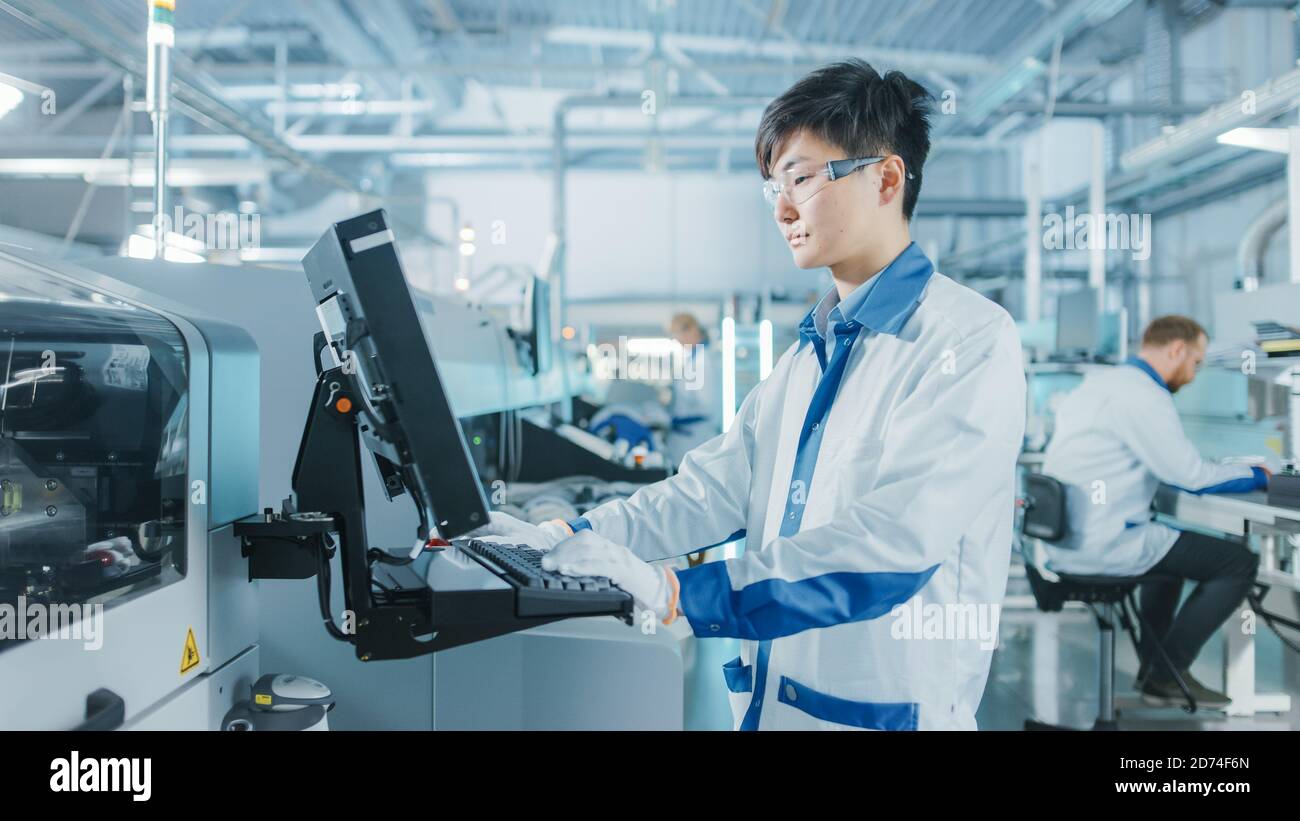 In der High-Tech-Fabrik verwendet Asian Engineer Computer für die Programmierung Pick and Place Elektronische Maschinen für Leiterplatten Oberfläche Montieren Sie Die Baugruppe Stockfoto