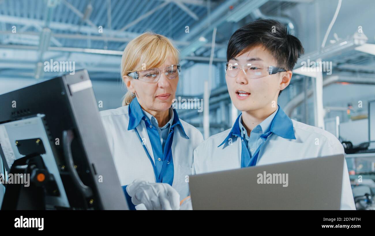 Auf High-Tech-Fabrik Asian Engineer Gespräche mit weiblichen Vorgesetzten, verwenden Sie Computer für die Programmierung Pick-and-Place elektronische Maschinen für gedruckte Schaltung Stockfoto