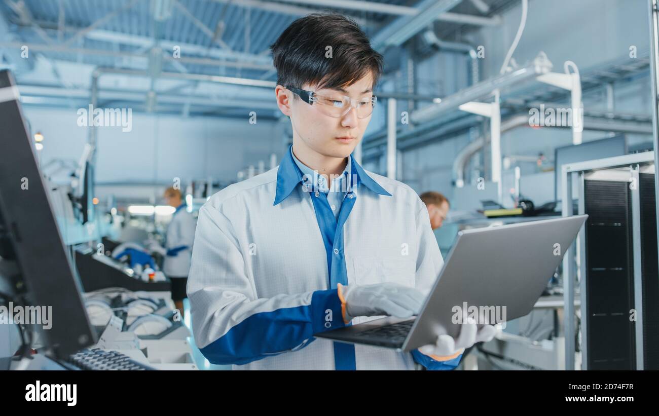 Auf High-Tech-Fabrik Asian Engineer verwendet Laptop-Computer für die Programmierung Pick and Place Elektronische Maschinen für Leiterplatten Oberfläche Halterung Stockfoto