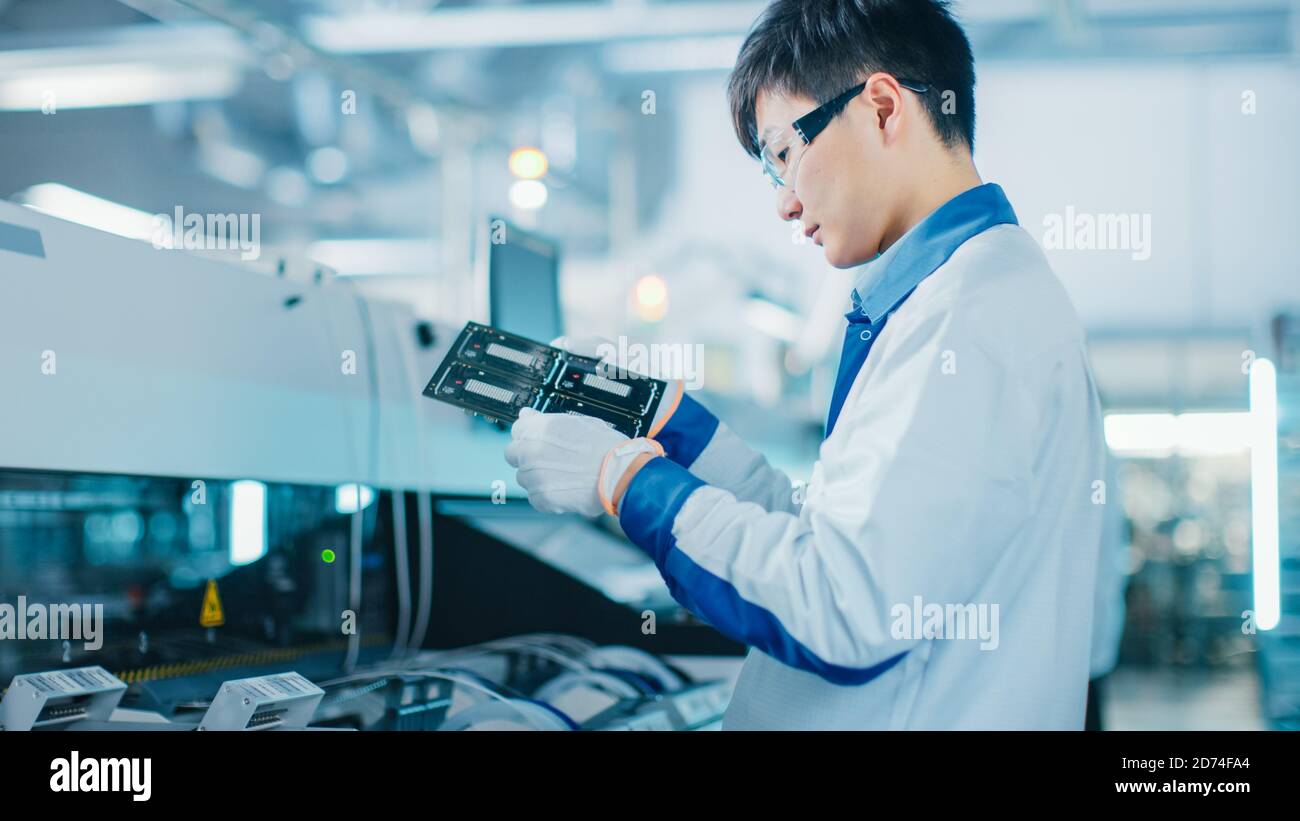 High-Tech Factory: Qualitätsingenieur prüft elektronische Leiterplatten-IT auf Schäden. In der Background Assembly Line für Leiterplatte mit Stockfoto