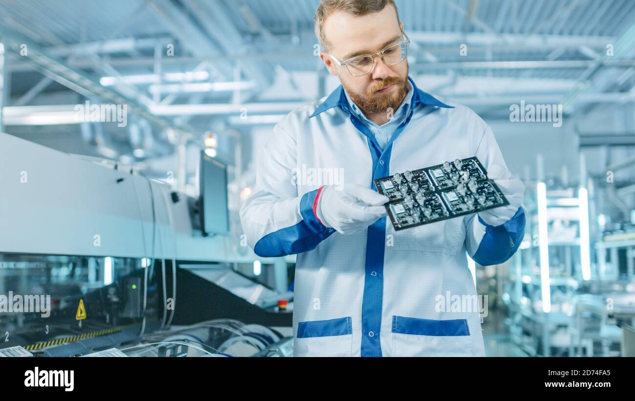 High-Tech Factory: Qualitätskontrolle Inspektor prüft elektronische Leiterplatten-IT auf Schäden. In der Background Assembly Line für Leiterplatte mit Stockfoto