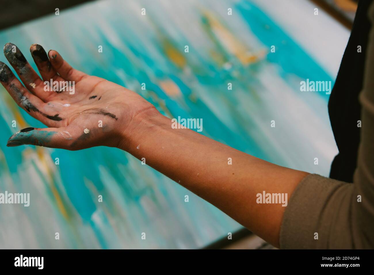 Frau Künstlerhand mit Farbe bedeckt, abstrakte Kunst im Hintergrund. Horizontale Komposition, Vollformat, Fokus auf den Vordergrund. Stockfoto