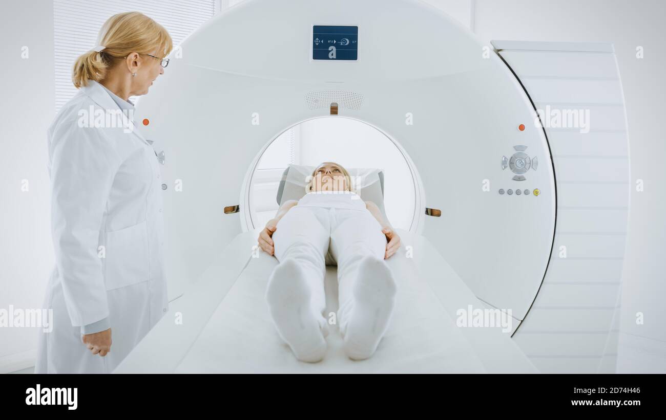 Im medizinischen Labor kontrolliert die Radiologin eine MRT- oder CT- oder PET-Untersuchung mit einer Patientin, die sich einem Verfahren unterziehen wird. Der Arzt Führt Notfallscans Durch Stockfoto