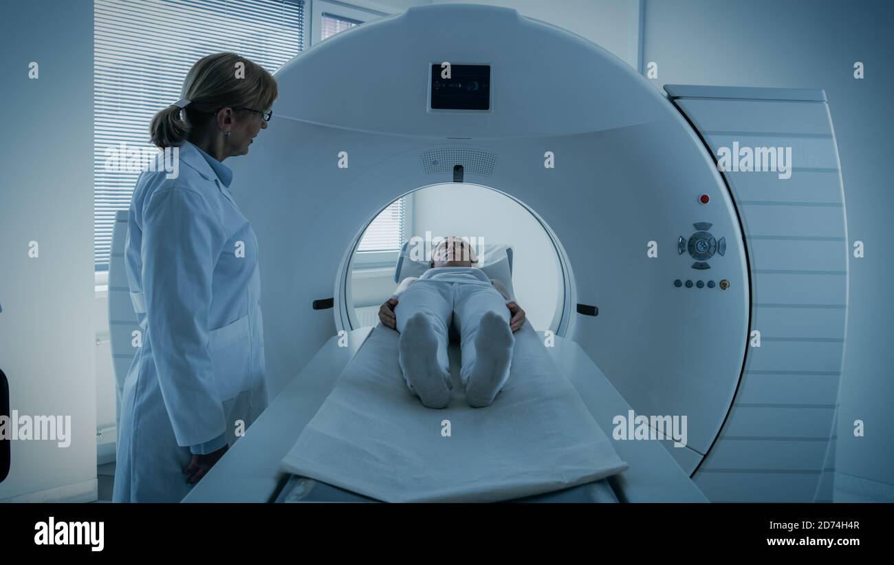 Im medizinischen Labor kontrolliert die Radiologin eine MRT- oder CT- oder PET-Untersuchung mit einer Patientin, die sich einem Verfahren unterziehen wird. Der Arzt Führt Notfallscans Durch Stockfoto