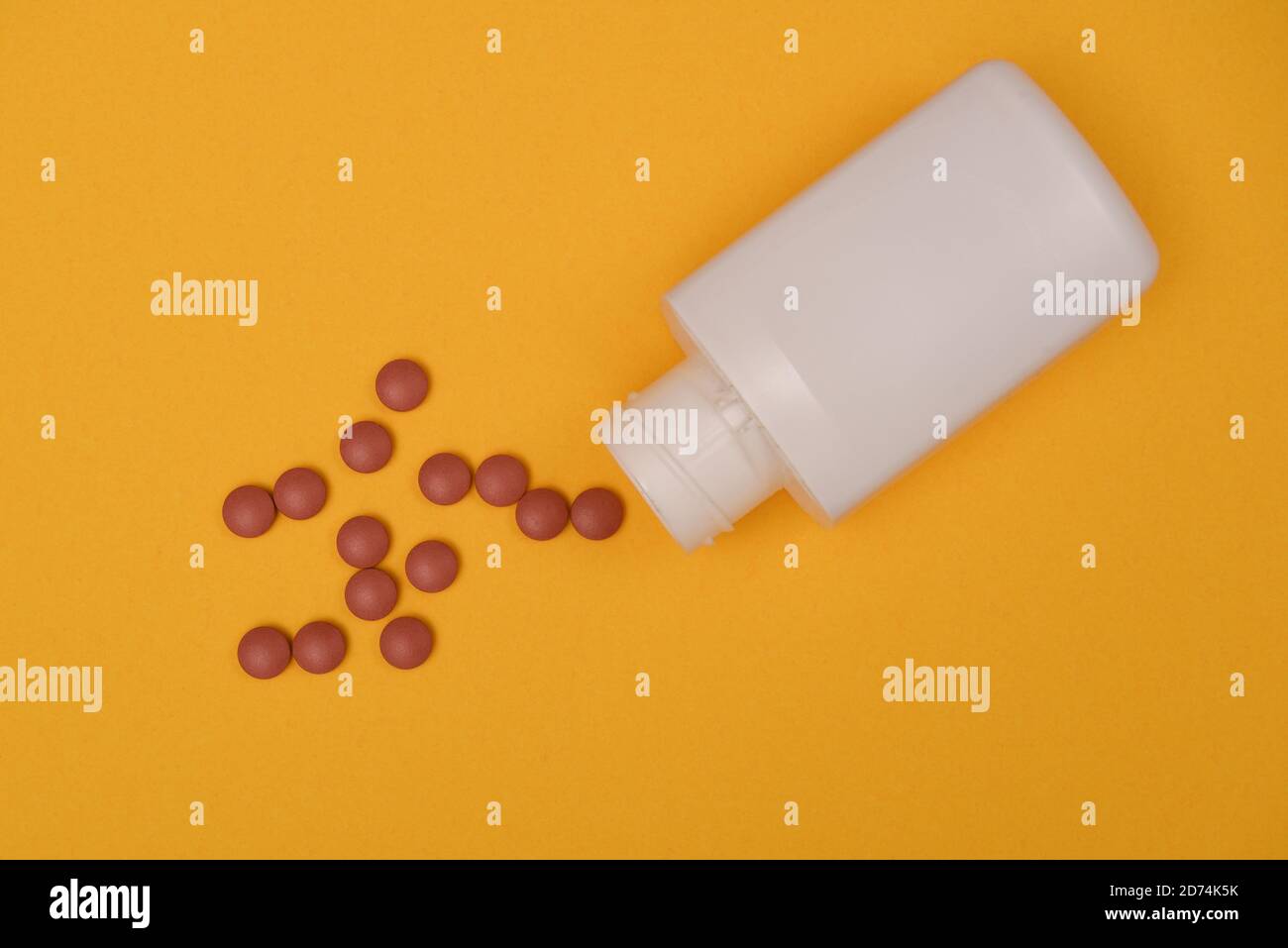 Leere Pillenflasche und Tabletten auf gelbem Hintergrund Stockfoto