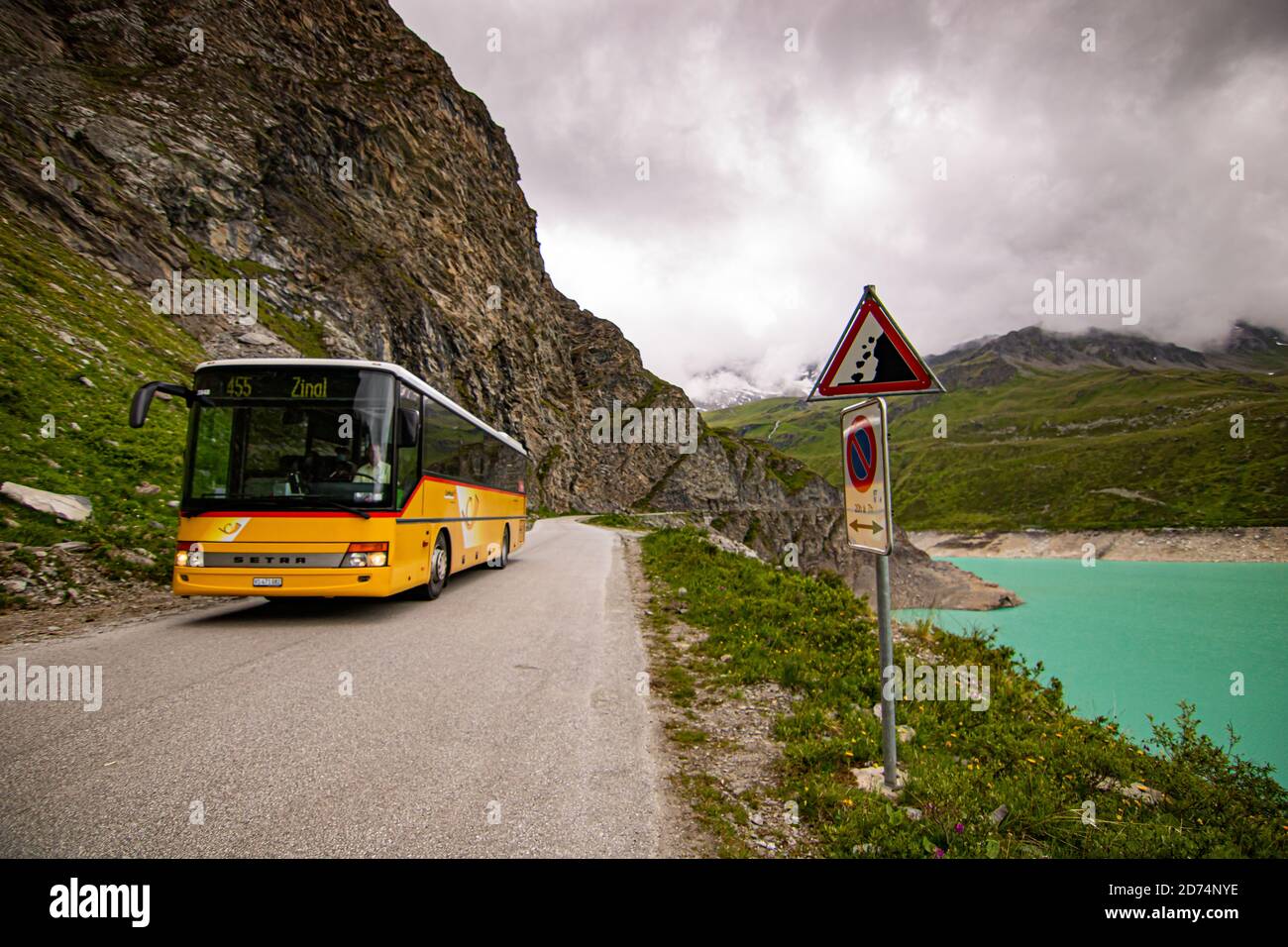 Gelber Bus der öffentlichen Verkehrsmittel. Bushaltestelle auf dem Lac de Moiry in den Schweizer Alpen. In Grimentz Vallis, Schweiz. Stockfoto