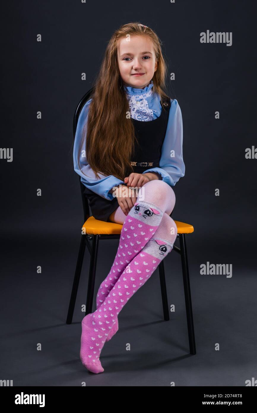 Kleine niedliche Mädchen posiert, während auf einem Stuhl sitzen Stockfoto