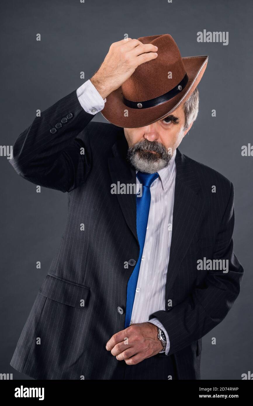 Älterer expressiver Dandy-Mann in einem Anzug mit Krawatte Aggressiv tritt und zieht seinen Hut ab Stockfoto