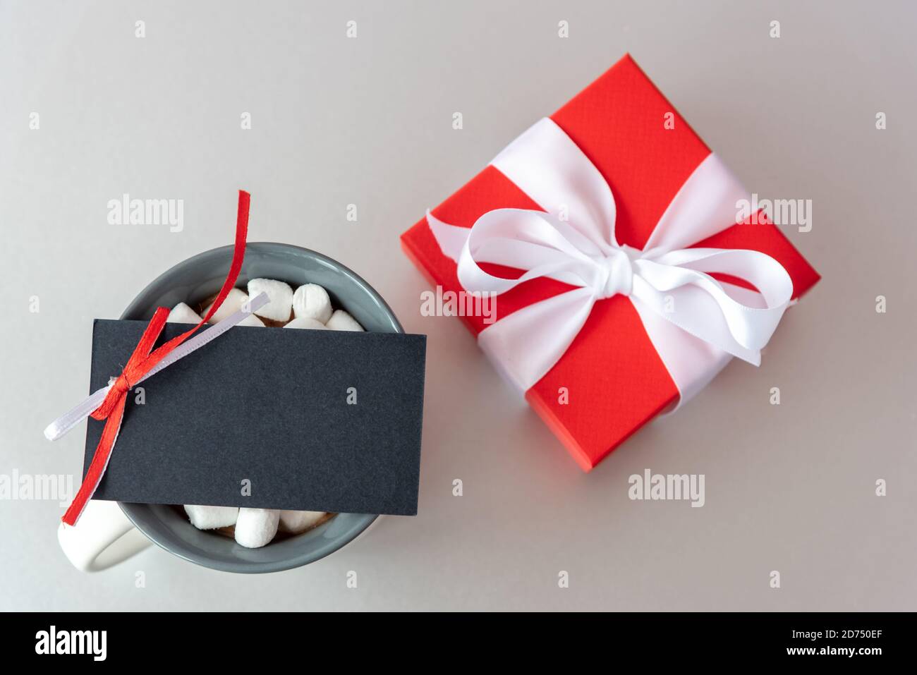 Leere schwarze Karte auf Tasse mit Marshmallow und rotem Geschenk Feld Stockfoto