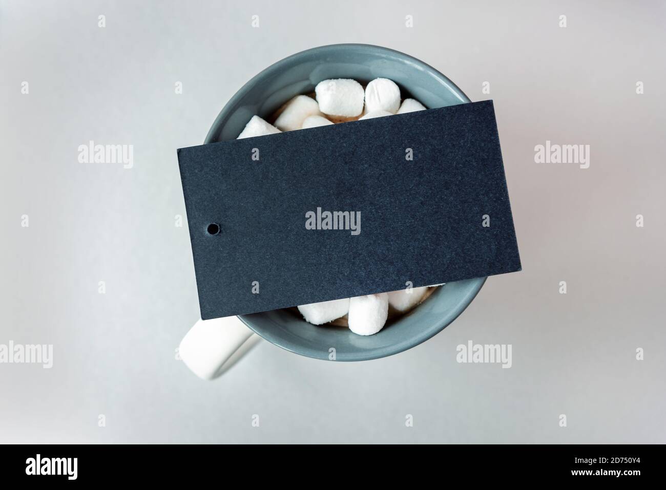 Leere schwarze Karte auf Tasse Kakao mit Marshmallow auf Grau Stockfoto