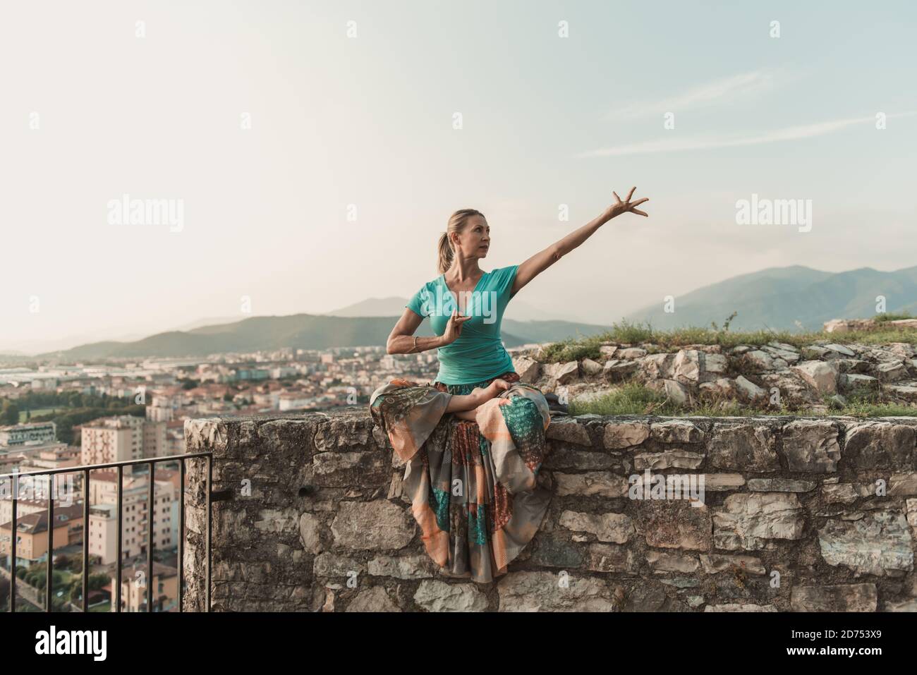 Erwachsene Frau macht Sport. Yogalehrer macht ein Asana an der alten Stadtmauer. Stockfoto