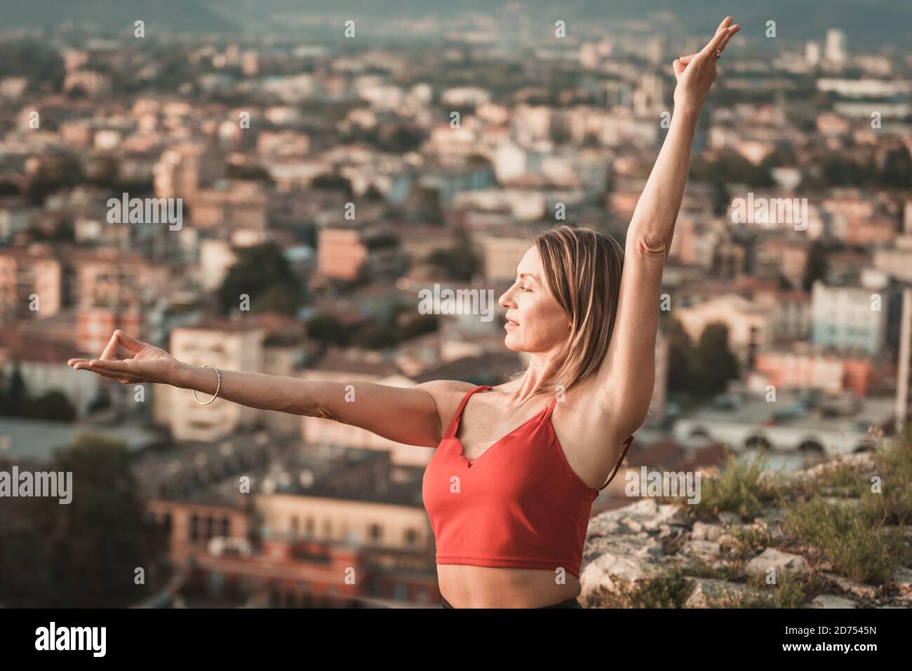 Erwachsene Frau macht Sport. Yogalehrer macht ein Asana an der alten Stadtmauer. Stockfoto