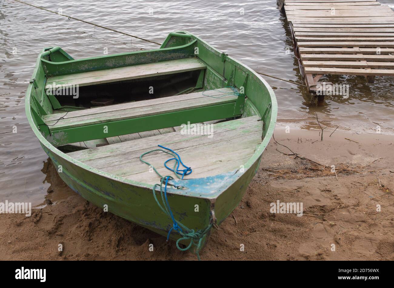 Shabby Holzboot grün lackiert mit zwei Bänken zum Rudern An einem kleinen  Pier am Ufer am Seil festgemacht bucht von See oder Fluss an bewölkten Tag  Stockfotografie - Alamy