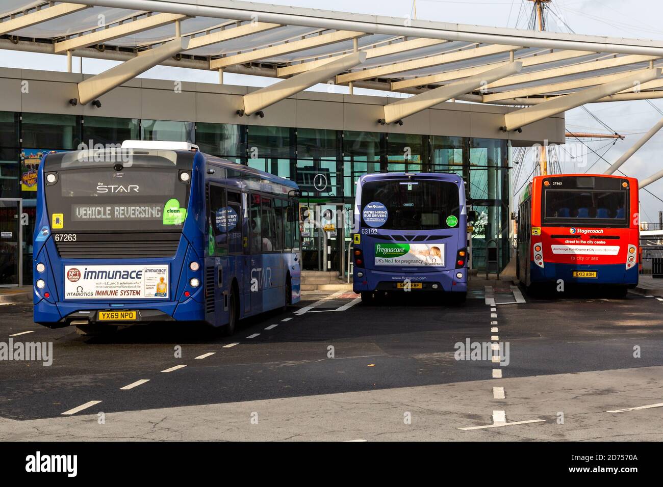 Ein einfacher Busservice, der neben zwei Terminals in ein Busterminal fährt Busse in Buchten geparkt Stockfoto